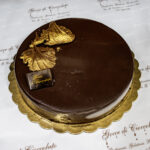 Scopri la Torta Rocher di Gocce di Cioccolato, una deliziosa mousse al cioccolato con un ripieno cremoso Rocher e un sottile strato di biscuit classico.